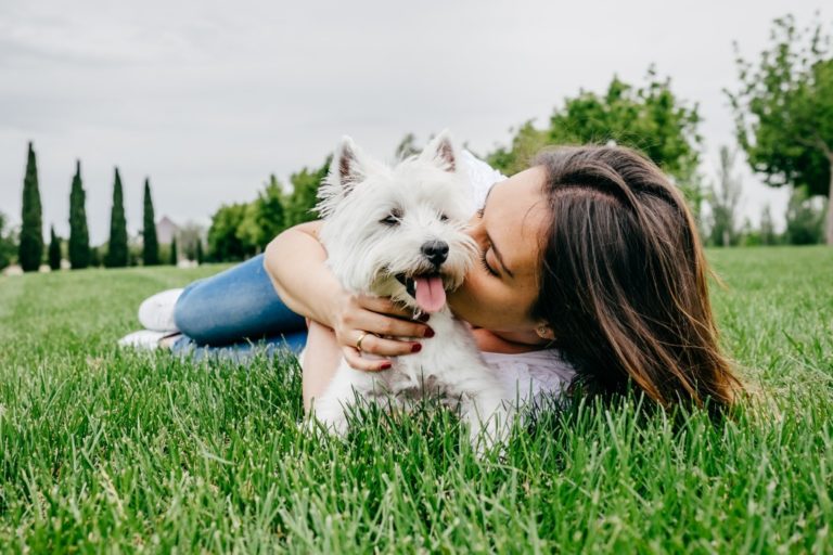 woman and her dog playing on the grass